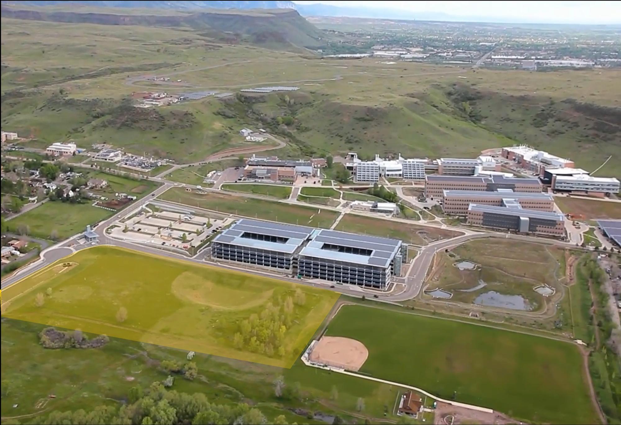 Aerial photo looking west over the GLO Park site, highlighted in yellow, with the National Laboratory of the Rockies campus beyond and the foothills and Golden in the distance